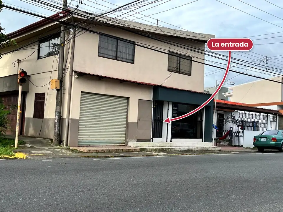 Entrada de Arte en Uñas Raquel: puerta de reja negra junto a la vitrina con marco gris oscuro