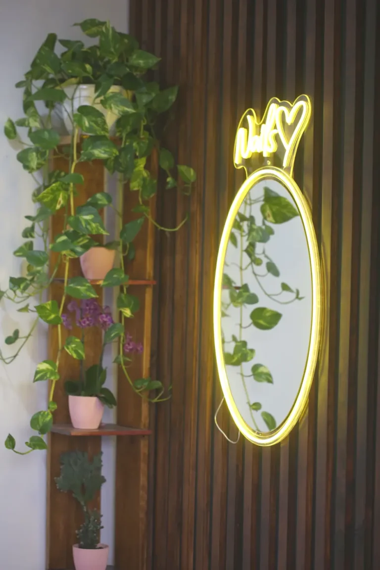 Espejo ovalado con neón y plantas en el salón Arte en Uñas Raquel