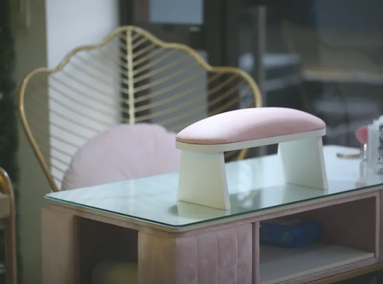 Mesa de manicure con cojín rosado y silla dorada en Arte en Uñas Raquel